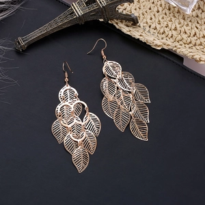 Macro view of multi-layered hollow leaf drop earrings with polished gold finish