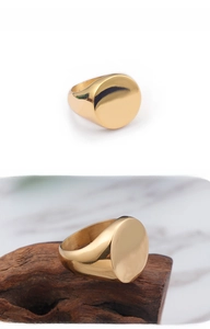 Macro shot of polished gold signet ring showcasing smooth round face and solid steel band