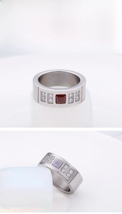 Close-up of wide titanium steel ring with square red gemstone and side rhinestones