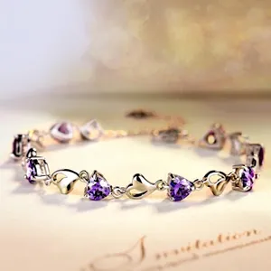 Detailed macro view of a silver-tone heart bracelet featuring purple amethyst-like stones.
