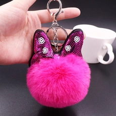 Detailed view of pink plush ball keychain with sequin polka dot bow and silver metal ring