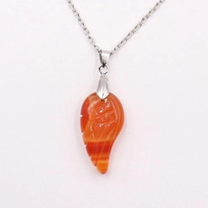 Detailed view of an orange carnelian wing pendant with silver chain and natural stone textures