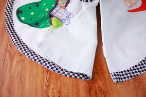 Detail of white Christmas tree skirt showing Santa Claus and holiday stocking patterns