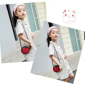 Detail of red ladybug shaped crossbody bag for kids with black polka dots and rope strap