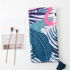 Détail d'un châle imprimé avec flamants roses, feuilles de palmier et pompons bleus