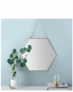 Detalle de espejo hexagonal de latón dorado con cadena de metal sobre pared azul