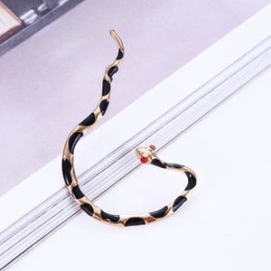 Macro shot of gold snake earring with black enamel and sparkling red crystal eyes