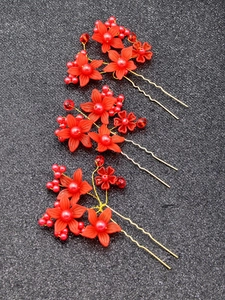 Detail of three red floral U-shaped hair pins with golden metal and pearls for bridal hair