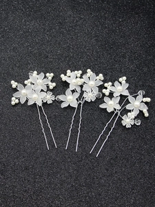 Detailed view of three white floral bridal hair pins with pearls and crystal beads