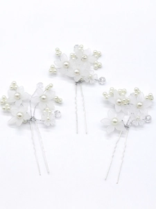 Detailed view of three white floral bridal hair pins with pearls and silver wire