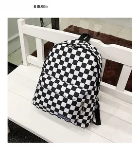 Detalle de la mochila de nailon a cuadros blancos y negros en un banco de madera