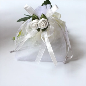 White organza drawstring gift bag with elegant ribbon bow and handmade rose decoration