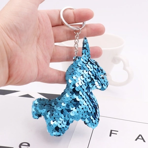 Blue reversible sequin unicorn keychain with metal ring being held by hand