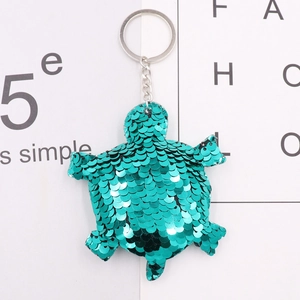 Macro detail of a green sequin sea turtle keychain with silver metallic ring