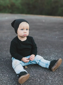 Outdoor shot of a toddler in a black cotton beanie and casual denim outfit set