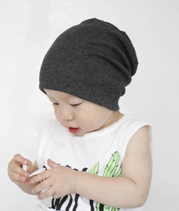 Infant wearing a dark grey cotton slouchy beanie showing the soft knitted texture and fit