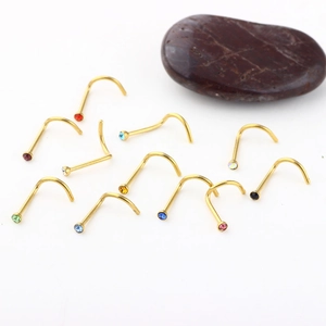 Close-up of golden L-shaped nose studs with colorful rhinestones on a white background