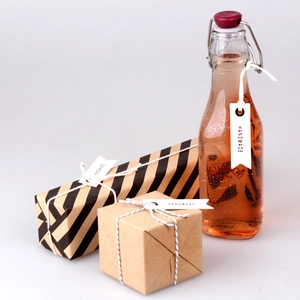 Handmade kraft paper gift labels with cotton string on rustic wrapped boxes and glass bottle