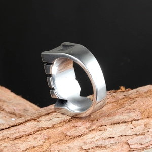 Close-up of silver stainless steel men's ring with groove detail on tree bark