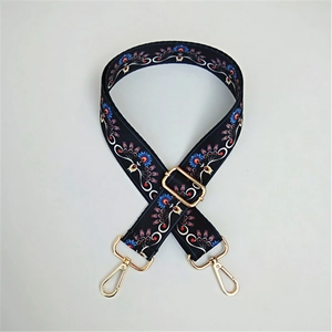 Detail of adjustable ethnic style bag strap with floral pattern and gold metal hardware