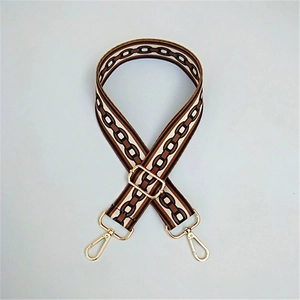Detail of adjustable woven bag strap with geometric chain pattern and gold metal hardware