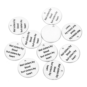 Macro detail of engraved stainless steel round charms with Not sisters by heart quote