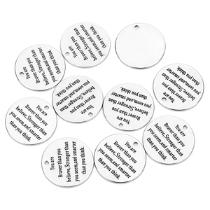 Detailed view of round stainless steel engraved charms with inspirational quotes for DIY jewelry