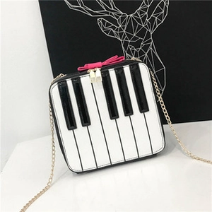 Detail of piano keyboard pattern bag with pink bow and gold chain strap