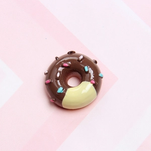 Close-up of a brown resin donut charm with colorful sprinkles on a striped background