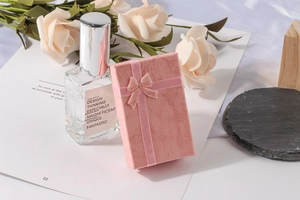 Pink textured jewelry gift box featuring a pink ribbon bow and elegant floral background