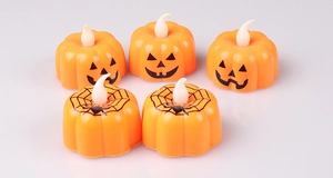 Detail of five orange LED pumpkin candles with jack-o-lantern faces and spider web patterns