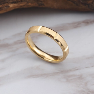 Bague minimaliste en acier inoxydable brossé doré sur un comptoir en marbre