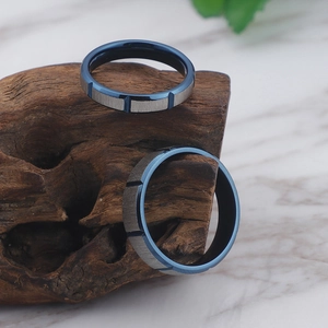 Brushed steel couple rings with blue inner band displayed on rustic wood over marble