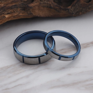 Classic blue and grey brushed stainless steel couple rings on a marble surface