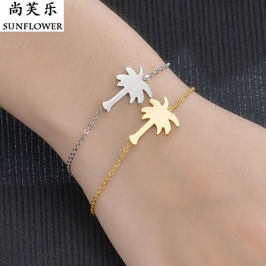 Macro shot of minimalist gold and silver palm tree charm bracelets on a textured background