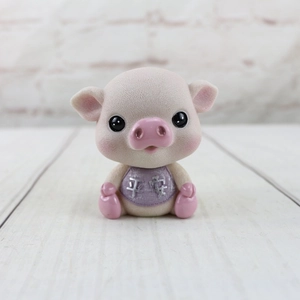 Détail de la figurine de porcelet floquée avec bavoir violet et texte de paix argenté