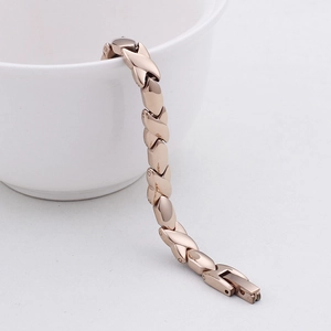 Rose gold magnetic stainless steel bracelet hanging on a white ceramic cup