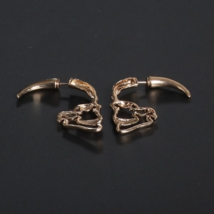 Close-up of golden hollow skull earrings with polished gothic punk aesthetic