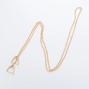 Detailed view of the double stirrup pendant on a gold horseshoe necklace for women