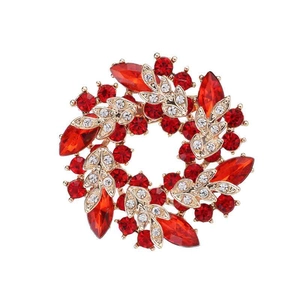 Elegant gold flower wreath brooch with red and clear crystals on white background