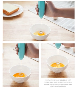 Detail of handheld electric whisk with stainless steel spiral head mixing egg in white bowl
