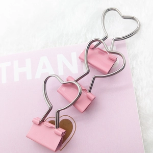 Detailed view of three pink heart-shaped metal binder clips on a soft decorative background