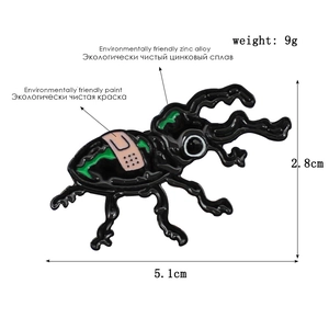 Macro shot of beetle enamel pin showing 5.1cm x 2.8cm dimensions and 9g weight details