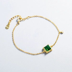 Detail shot of the S925 hallmark on a gold bracelet with green square gemstone