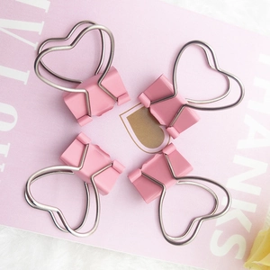 Set of four pink heart-shaped paper clips on a decorative pink background card