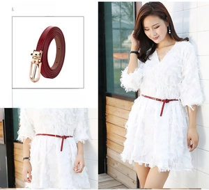 Detail of red thin leather belt with gold pin buckle worn on a white fringe dress