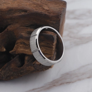 Silver brushed titanium steel ring with gold-tone accents on a rustic wood stand