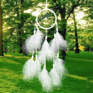 Handcrafted white dream catcher with feathers and beads against a forest background