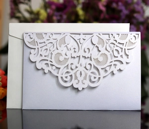 Detailed laser-cut floral pattern on a pearl white envelope and lavender wedding invitation
