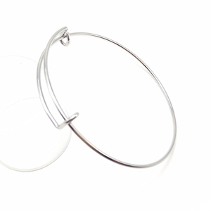 Close-up of a minimalist adjustable silver stainless steel wire bangle on white background